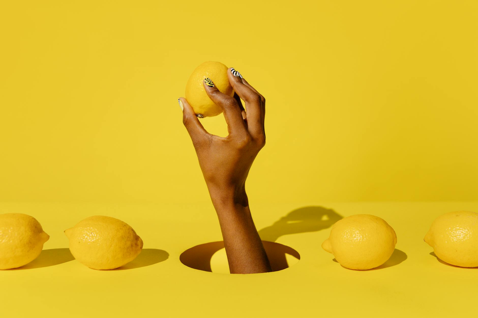 A yellow silicone vibrator surrounded by fresh fruit on a bright background
