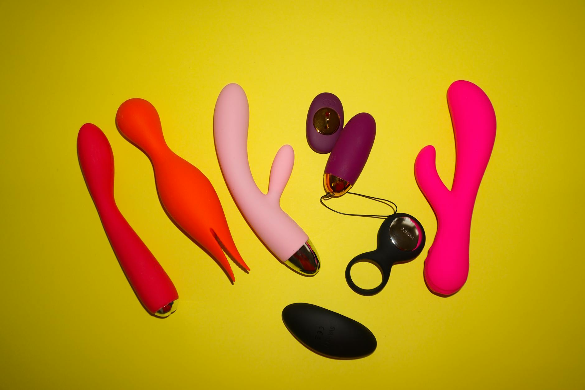 Colorful vibrators displayed on a bright yellow background, showing variety of shapes and designs